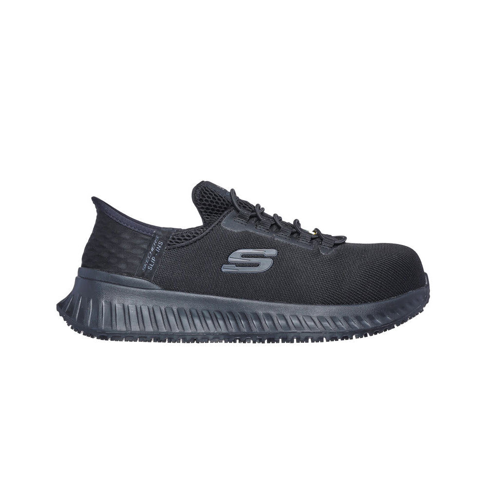A black Skechers Composite Toe Tilido Slip-ins sneaker with a flexible ribbed sole and logo on the side, displayed against a white background.