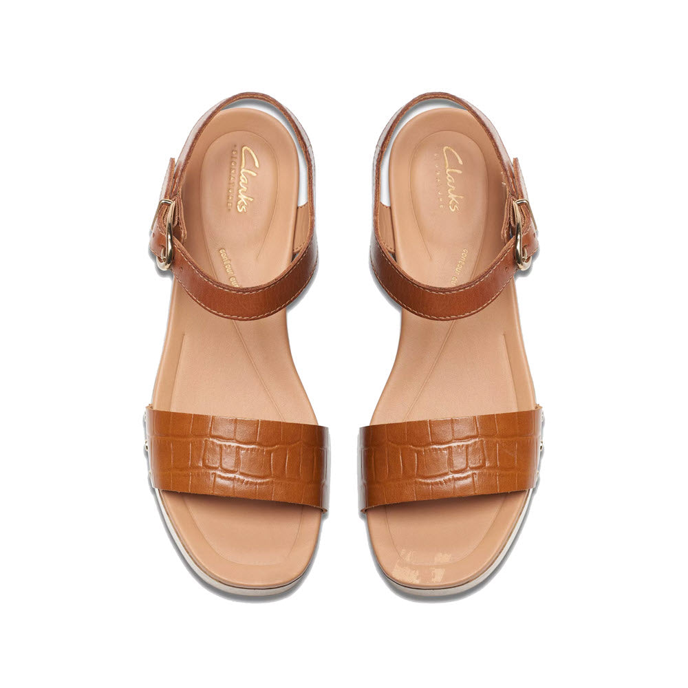 A pair of Clarks brand women&#39;s Sivanne Walk tan clog sandals with brown leather straps and buckles, displayed on a white background.