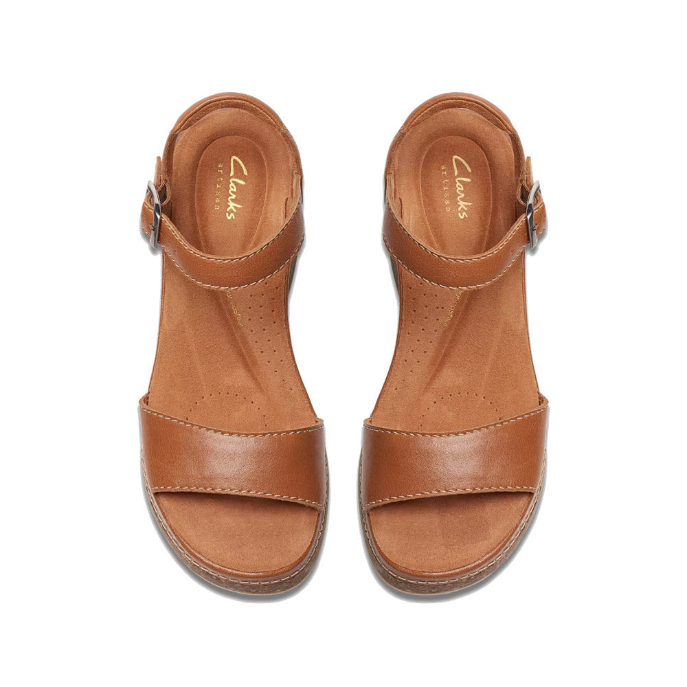 A pair of Clarks brand Clarks Kassanda Lily Tan sandals featuring brown leather with a single strap over the toe and an ankle buckle, displayed on a white background.