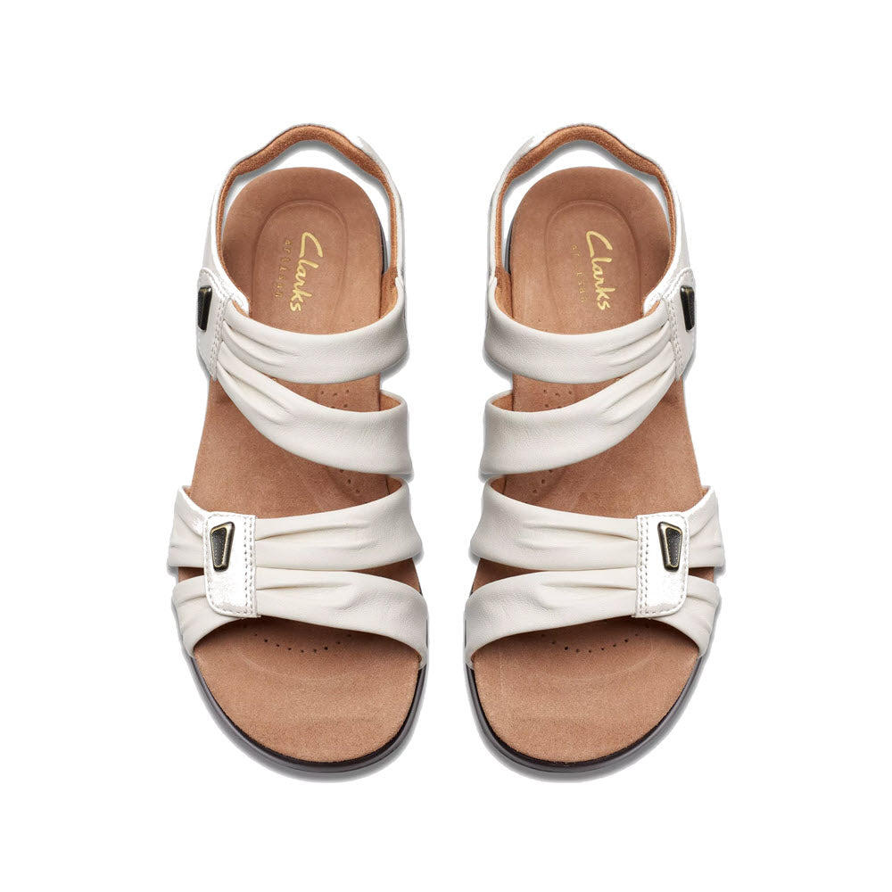 A pair of white Clarks Kitly Ave sandals with adjustable straps and buckles, displayed on a white background.