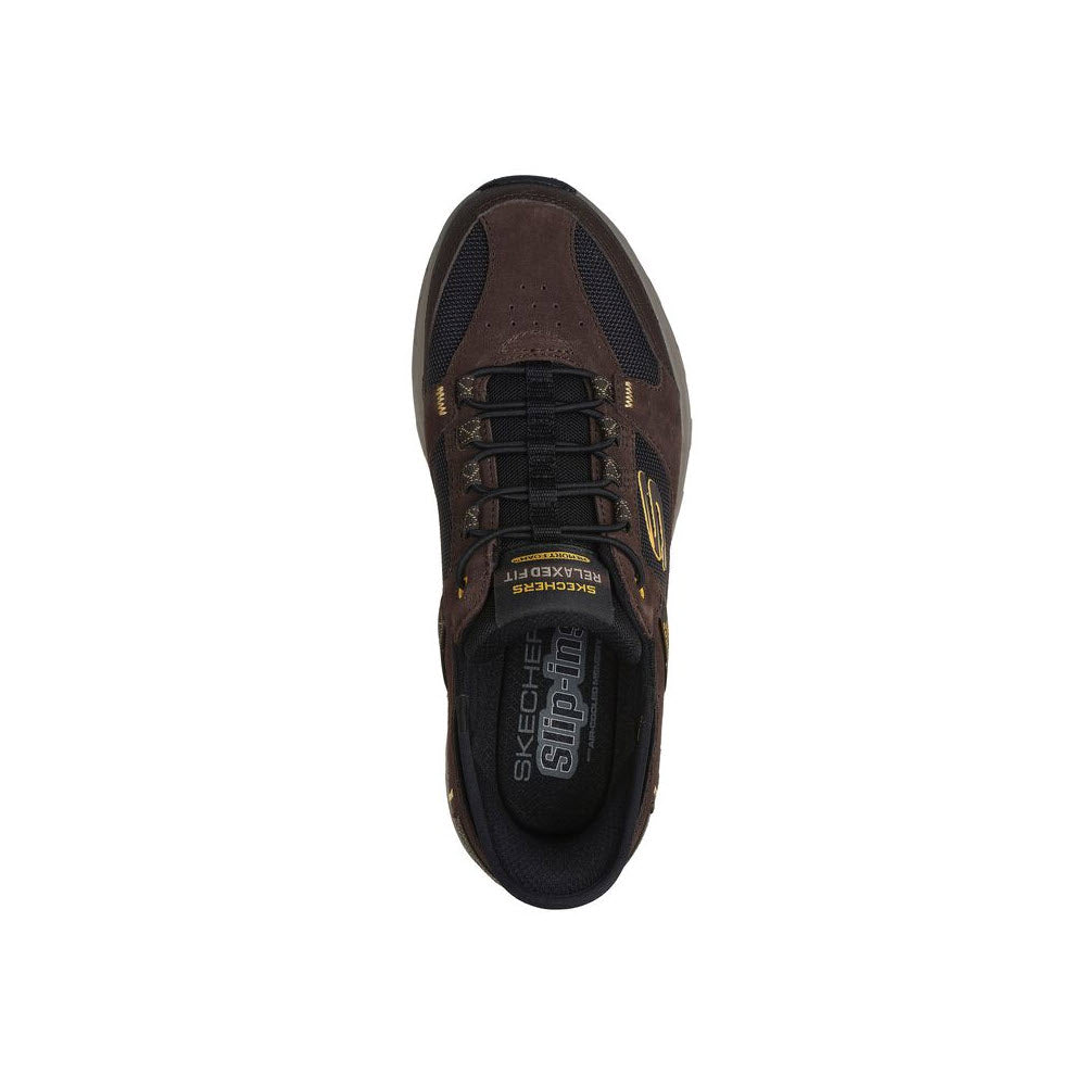 Top view of a brown Skechers Oak Canyon Slip-ins sneaker with black laces and gold accents, displaying logos on the tongue and side.