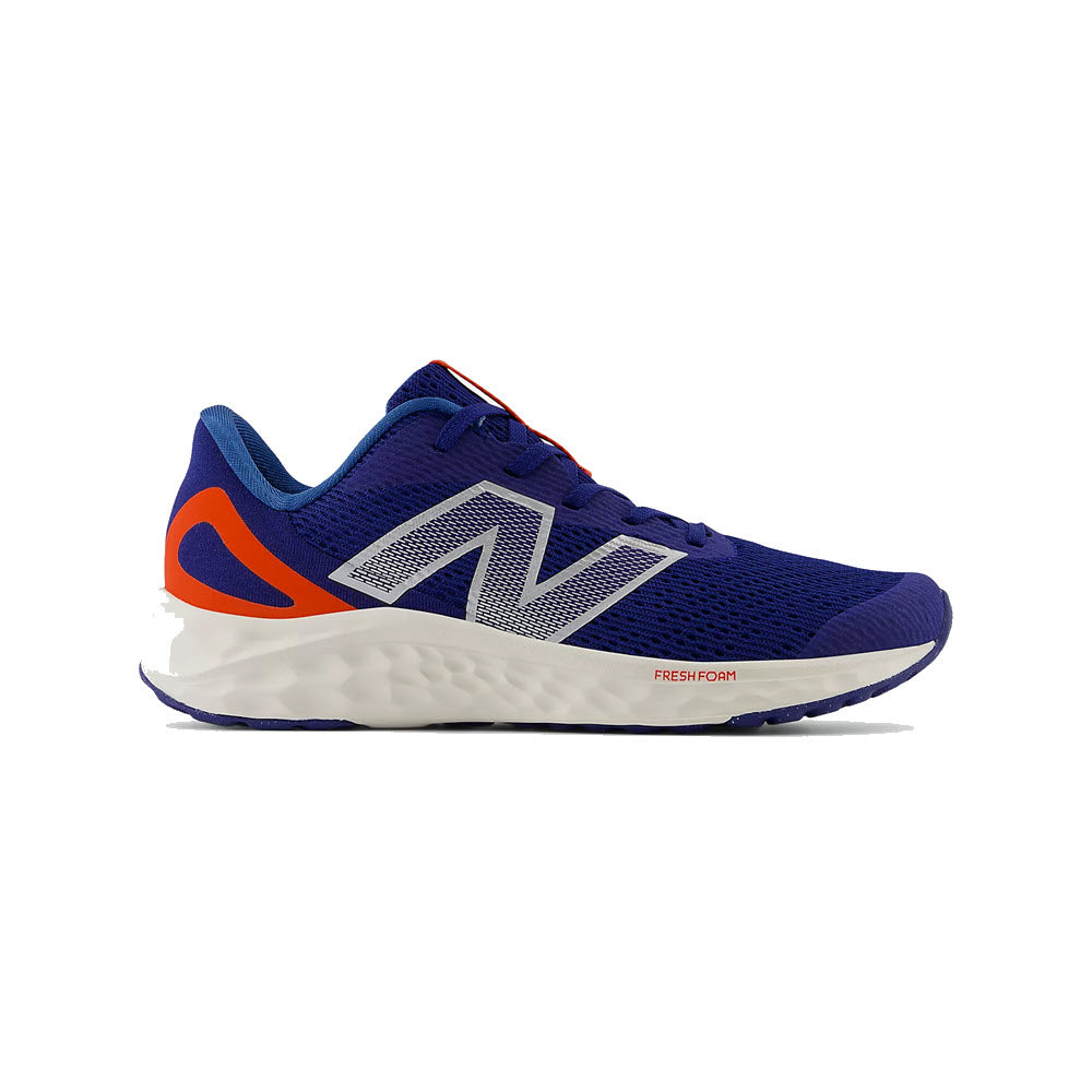The New Balance Arishi V4 Inkwell/Neo Flame - Kids is a sporty blue running shoe with a white sole, silver N logo, and orange accents for all-day comfort.