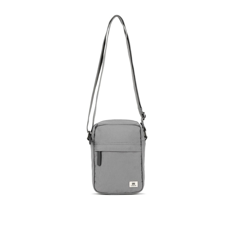 The Ori London BOND A crossbody ash with an adjustable strap and front zipper pocket, displayed on a white background. This lightweight urban accessory is perfect for daily use.