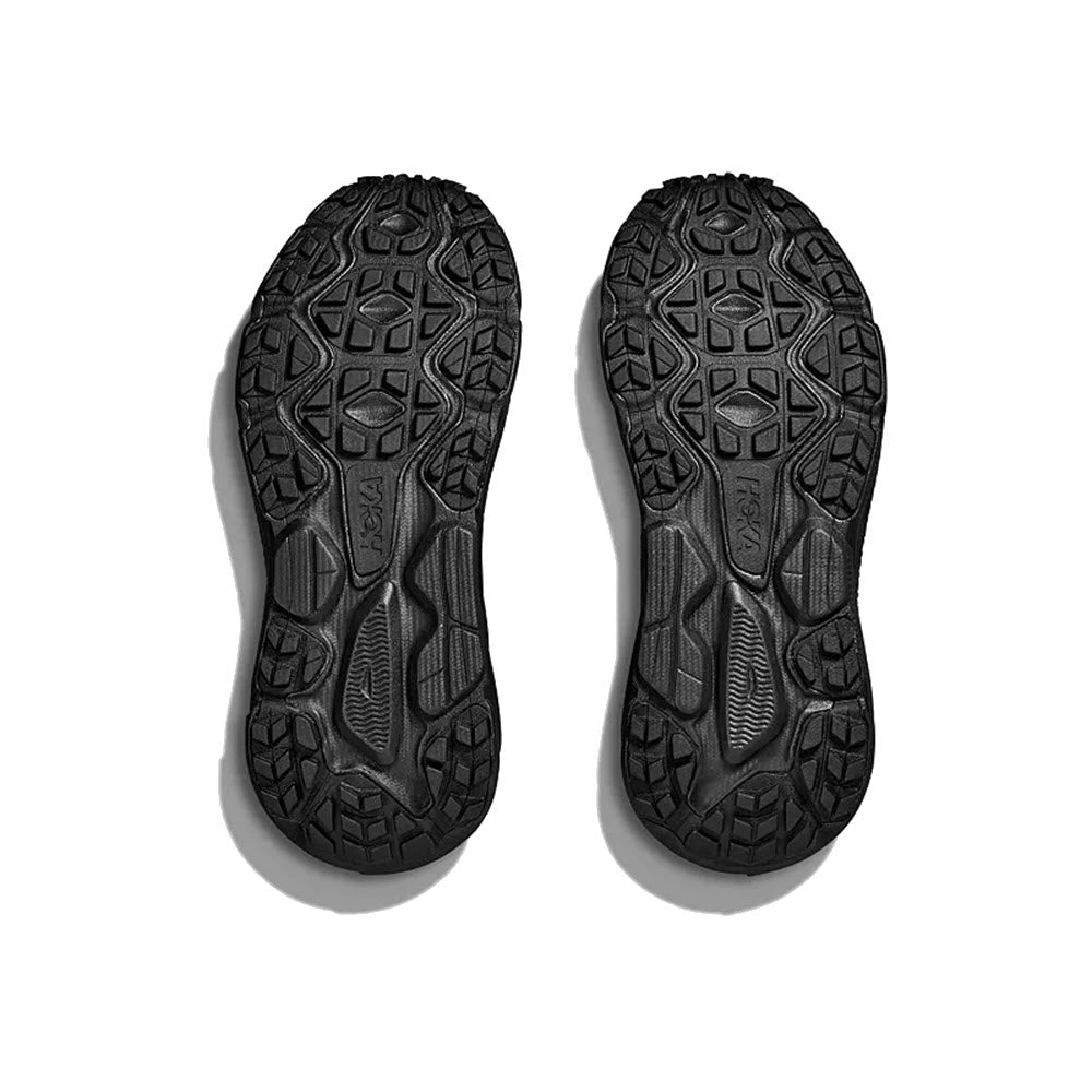 A pair of black Hoka Challenger ATR 7 GTX hiking boot soles displayed on a white background, showing detailed tread patterns and brand embossing.