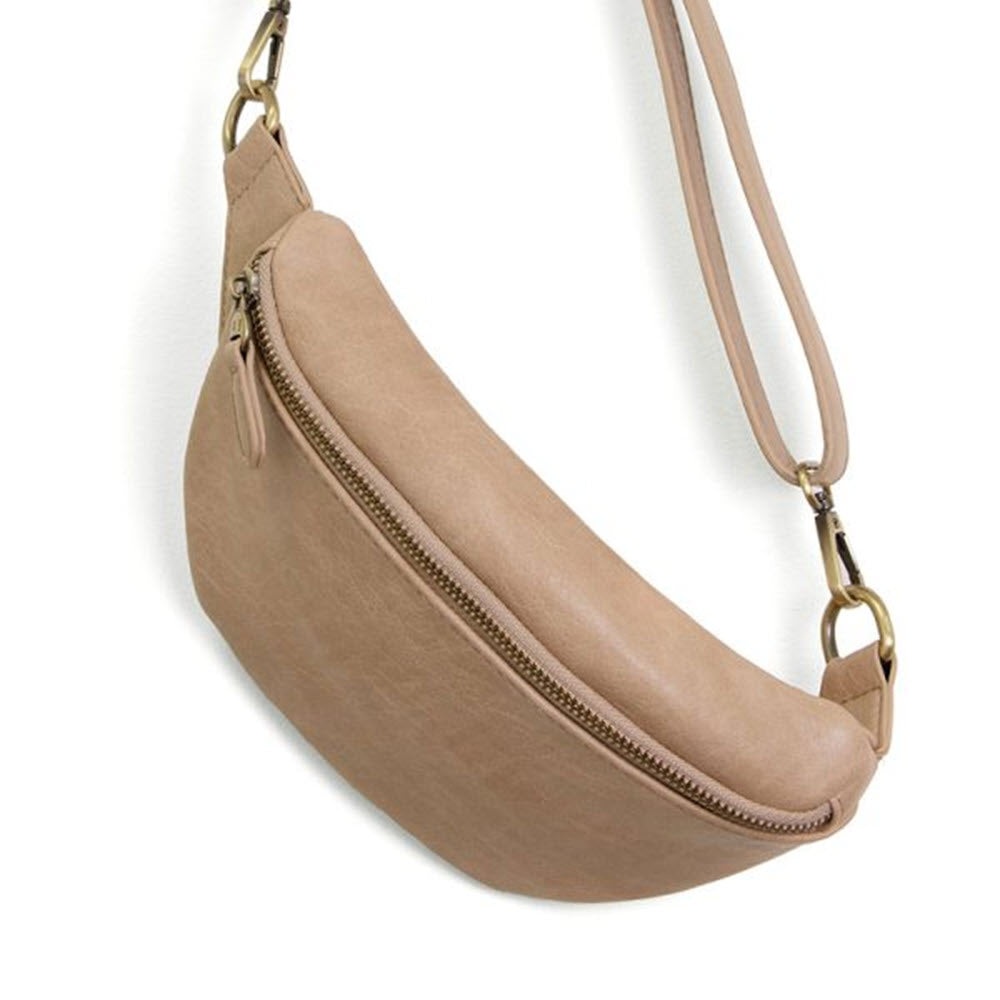 Beige crescent-shaped Joy Susan Shiloh sling belt bag buff with a zipper closure and a long, adjustable strap, isolated on a white background.