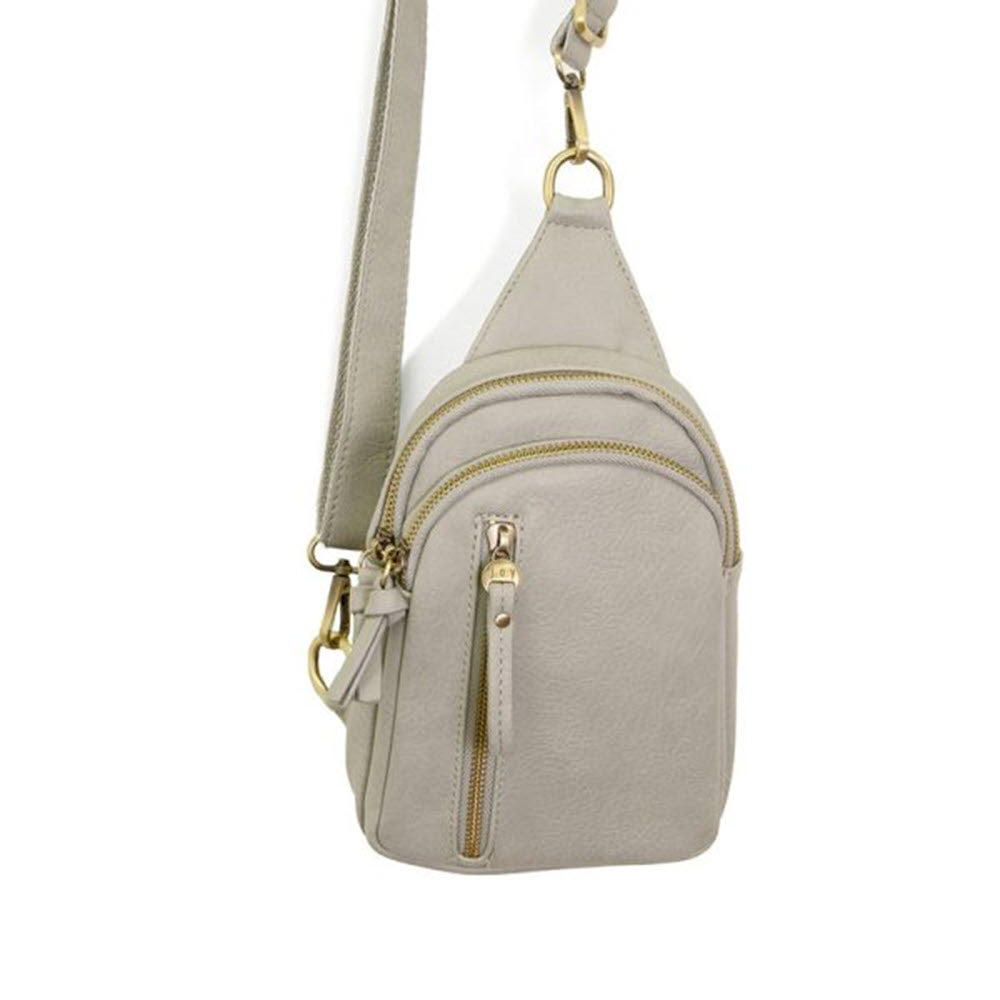 A Joy Susan Skylar sling bag crafted from vegan leather, featuring multiple zippers and a convertible strap, displayed on a white background.