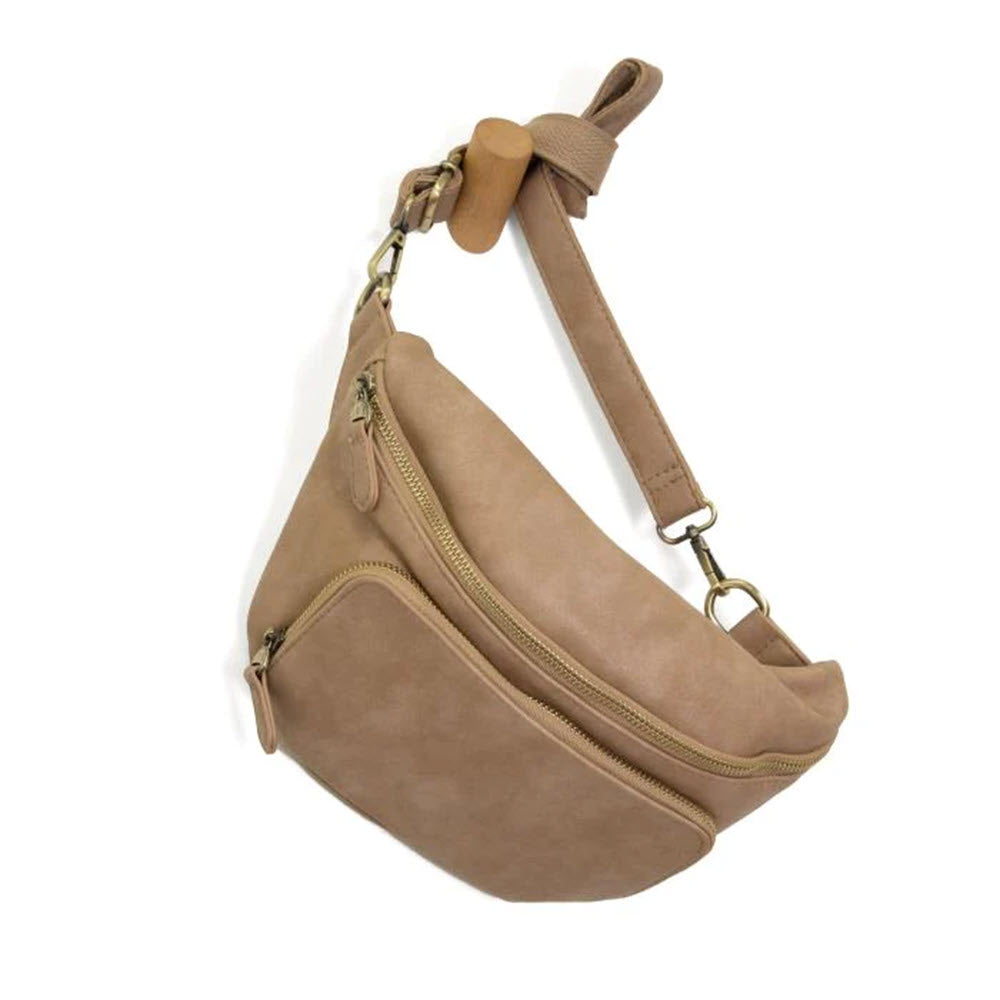 A Joy Susan Rory Sling-Belt Bag Tuscan Tan with a curved design and adjustable strap, displayed against a white background.