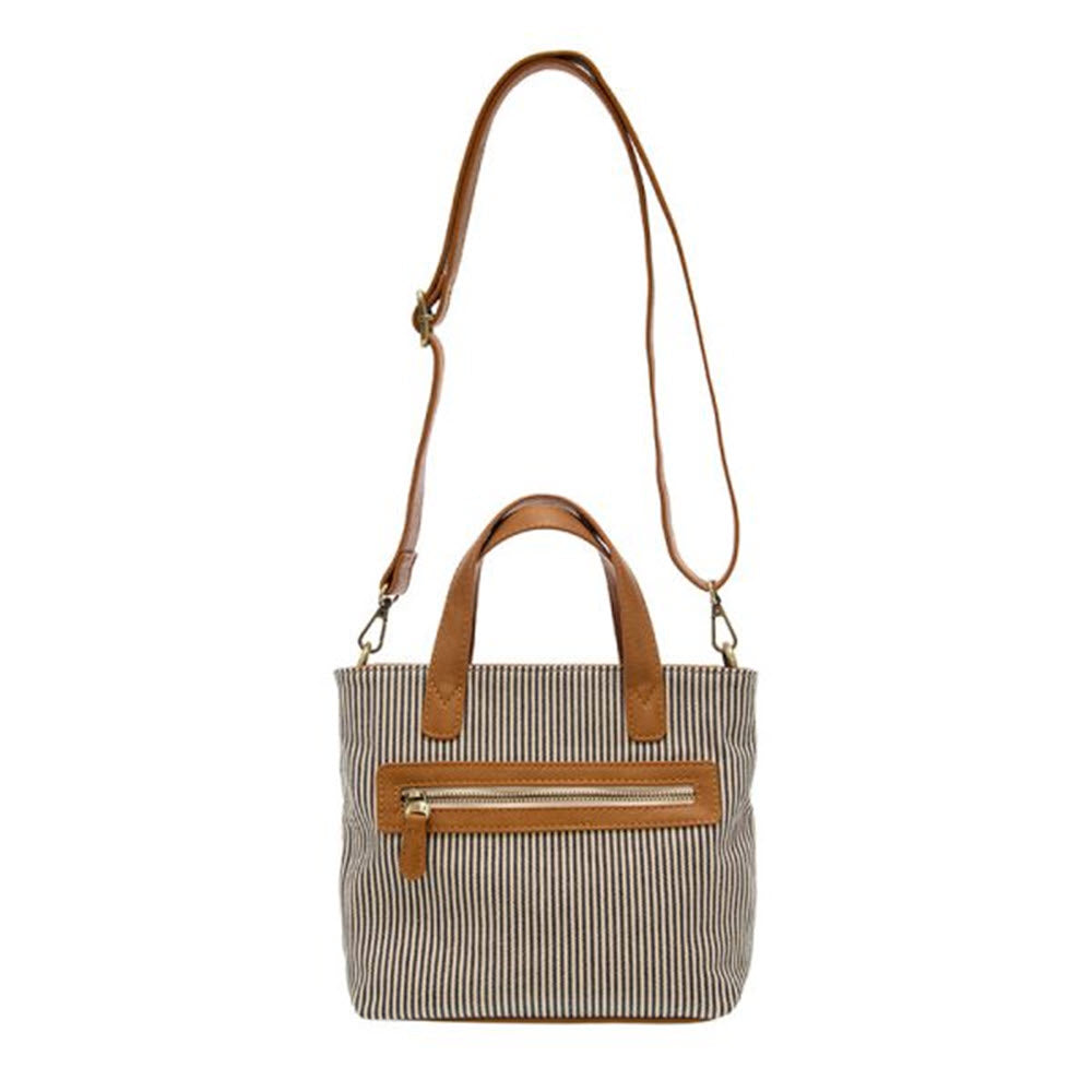 A JOY SUSAN Audrey Canvas Tote Crossbody Denim Pinstripe with brown leather handles and a long crossbody strap, featuring a front zipper pocket, isolated on a white background.