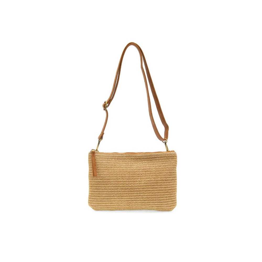 A small, rectangular, beige JOY SUSAN STRAW QUINN CROSSBODY NATURAL handbag with a brown crossbody shoulder strap and a zipper, isolated on a white background.