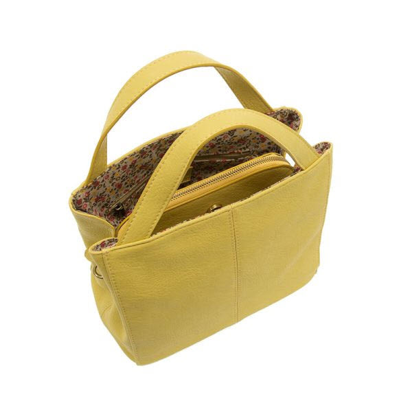 JOY SUSAN BRANDI CROSSBODY YELLOW vegan leather handbag with a floral-lined interior and zipper closure, displayed against a white background.