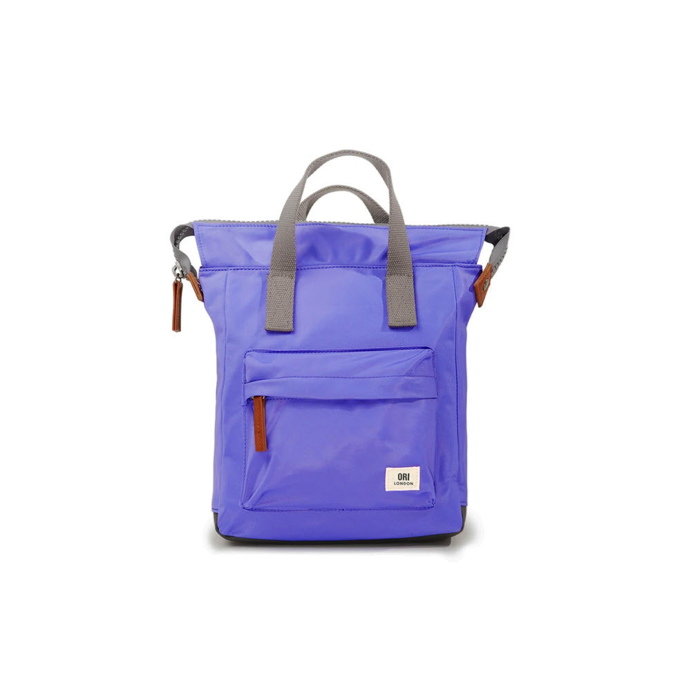 A bright purple ORI BANTRY B SMALL NYLON SIMPLE PURPLE backpack with a front pocket, sturdy zippers, and gray handles against a white background. Brand: Ori London