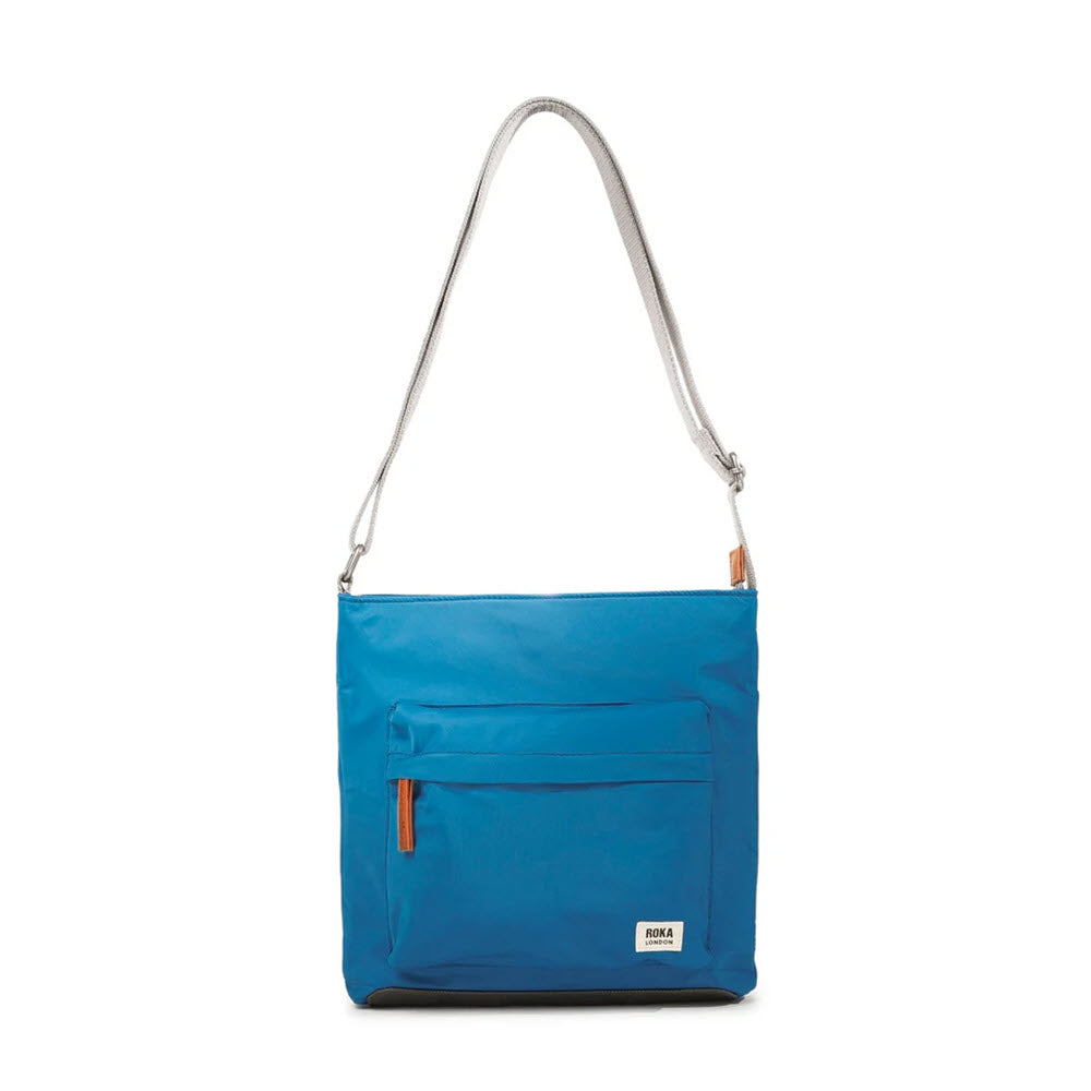 Bright blue ORI KENNINGTON B CROSSBODY SEAPORT with a silver strap and orange zipper details, displayed against a white background by Ori London.