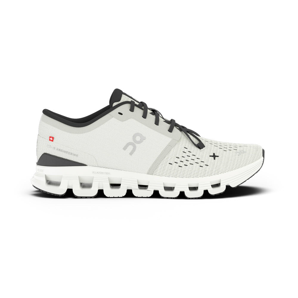 The ON CLOUD X 4 IVORY/BLACK - WOMENS by On Running is a light grey athletic shoe with a white segmented sole, black accents, mesh upper, lace-up closure, and Speedboard® technology for enhanced performance, shown from the side.