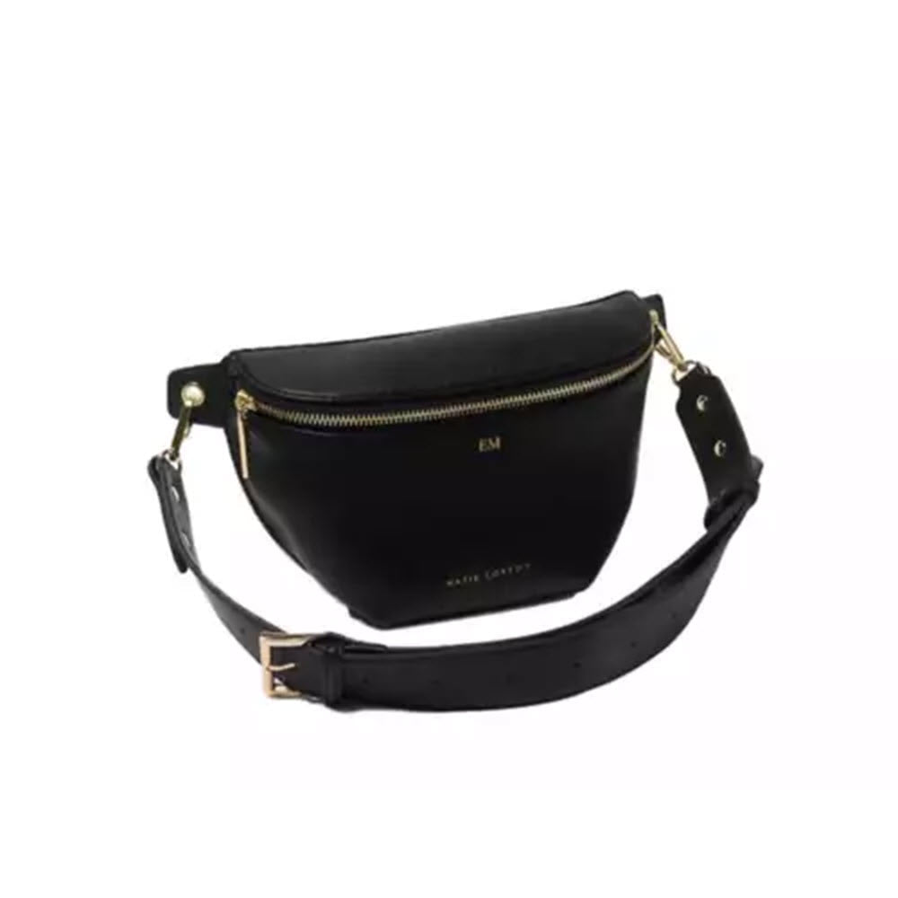 Katie Loxton Maya Belt Bag in Black vegan leather with gold zipper and adjustable strap, featuring embossed initials "em" on the front.
