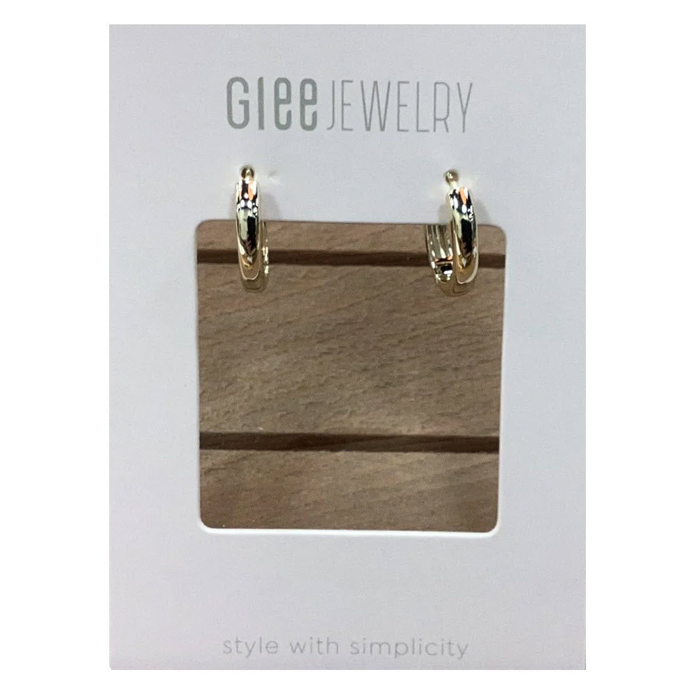 A pair of Glee Mini Circular Hoop Earrings Gold displayed on a wooden holder with the text &quot;hypoallergenic jewelry&quot; and &quot;style with simplicity&quot; above and below.