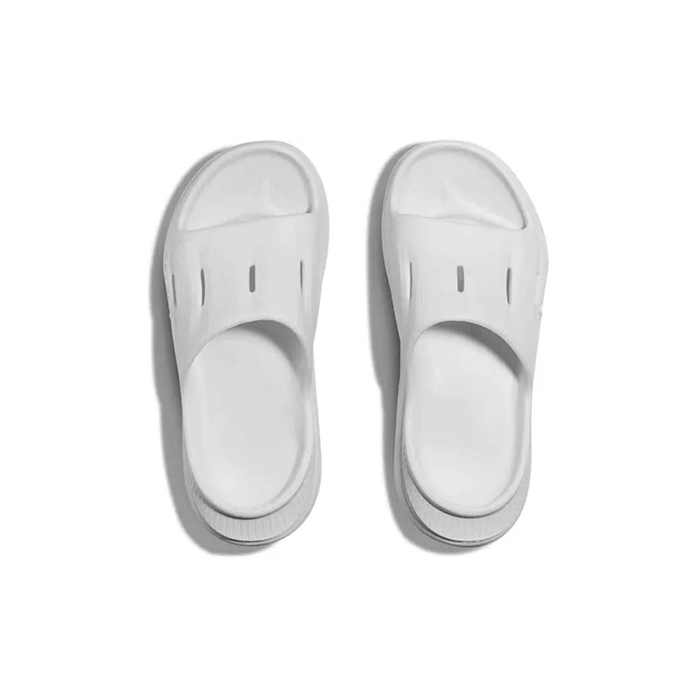 A pair of white HOKA ORA RECOVERY SLIDE 3 sandals with a sugarcane footbed isolated on a white background.