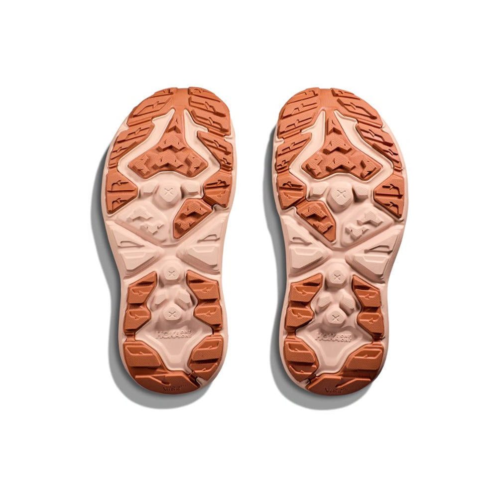 Pair of HOKA HOPARA 2 CREAM/CEDAR - WOMENS sandals soles with intricate tread pattern against a white background.