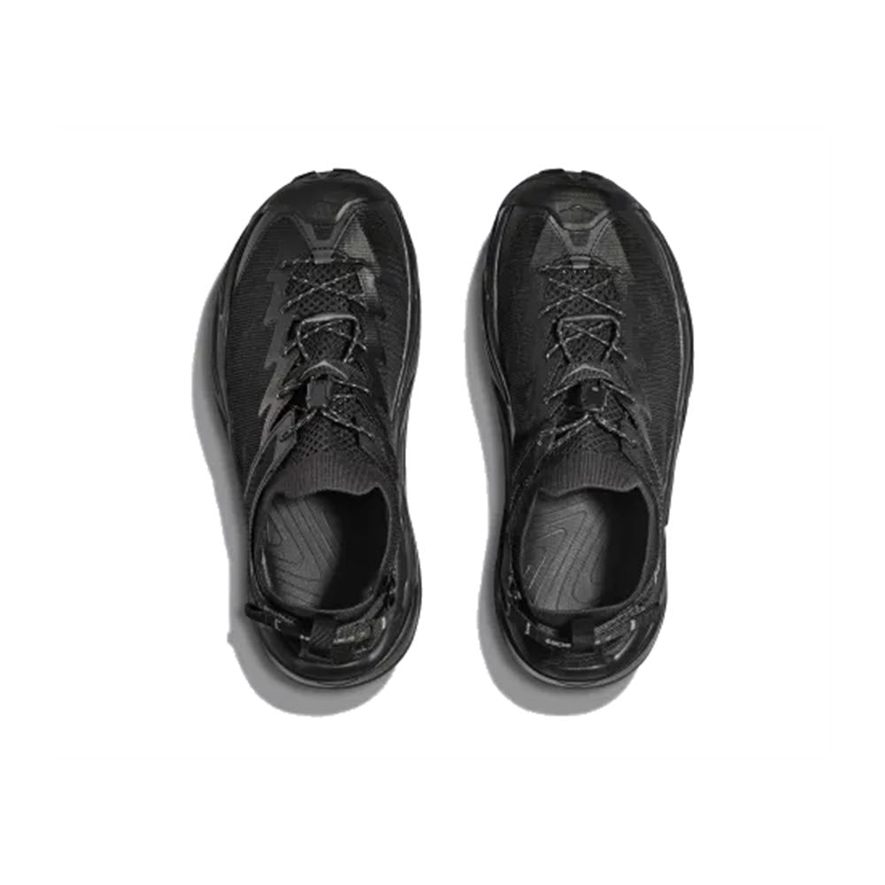 A pair of Hoka black sneakers with adjustable heel straps, viewed from above on a white background.