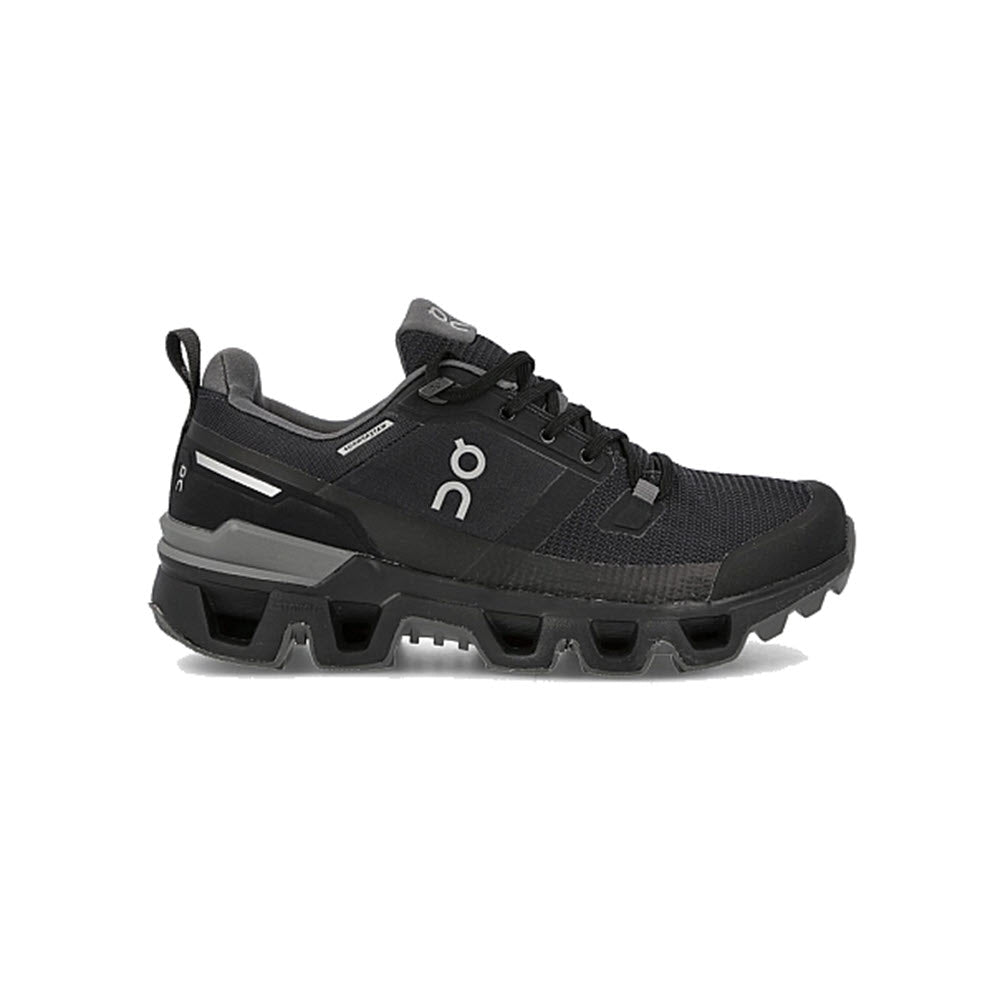 A single ON CLOUDWANDER WATERPROOF BLACK/ECLIPSE - WOMENS athletic sneaker with a chunky sole, featuring visible branding and laces, displayed against a white background. This lightweight sneaker is designed for outdoor performance.
