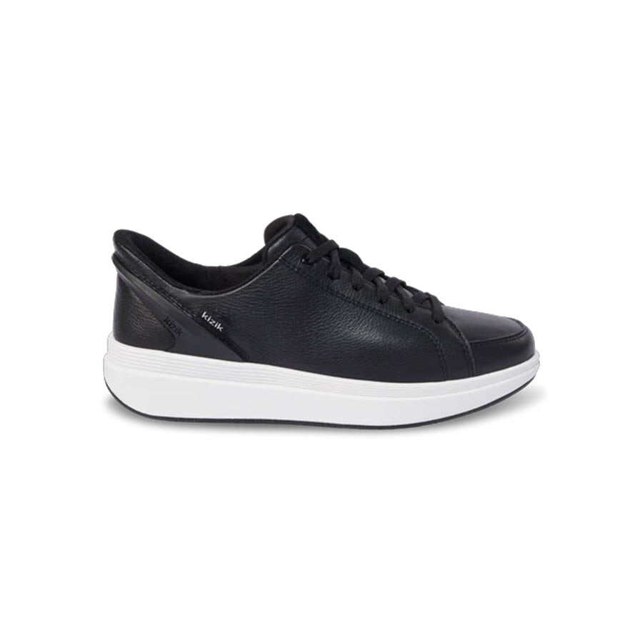 A black leather sneaker with a white rubber sole, shown from the side. The shoe has black laces and a low-top design, with subtle stitching and a textured finish.
