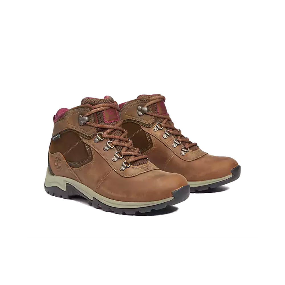 A pair of Timberland Mt. Maddsen Mid Waterproof Medium Brown hiking boots with pink accents and metal eyelets on a white background.