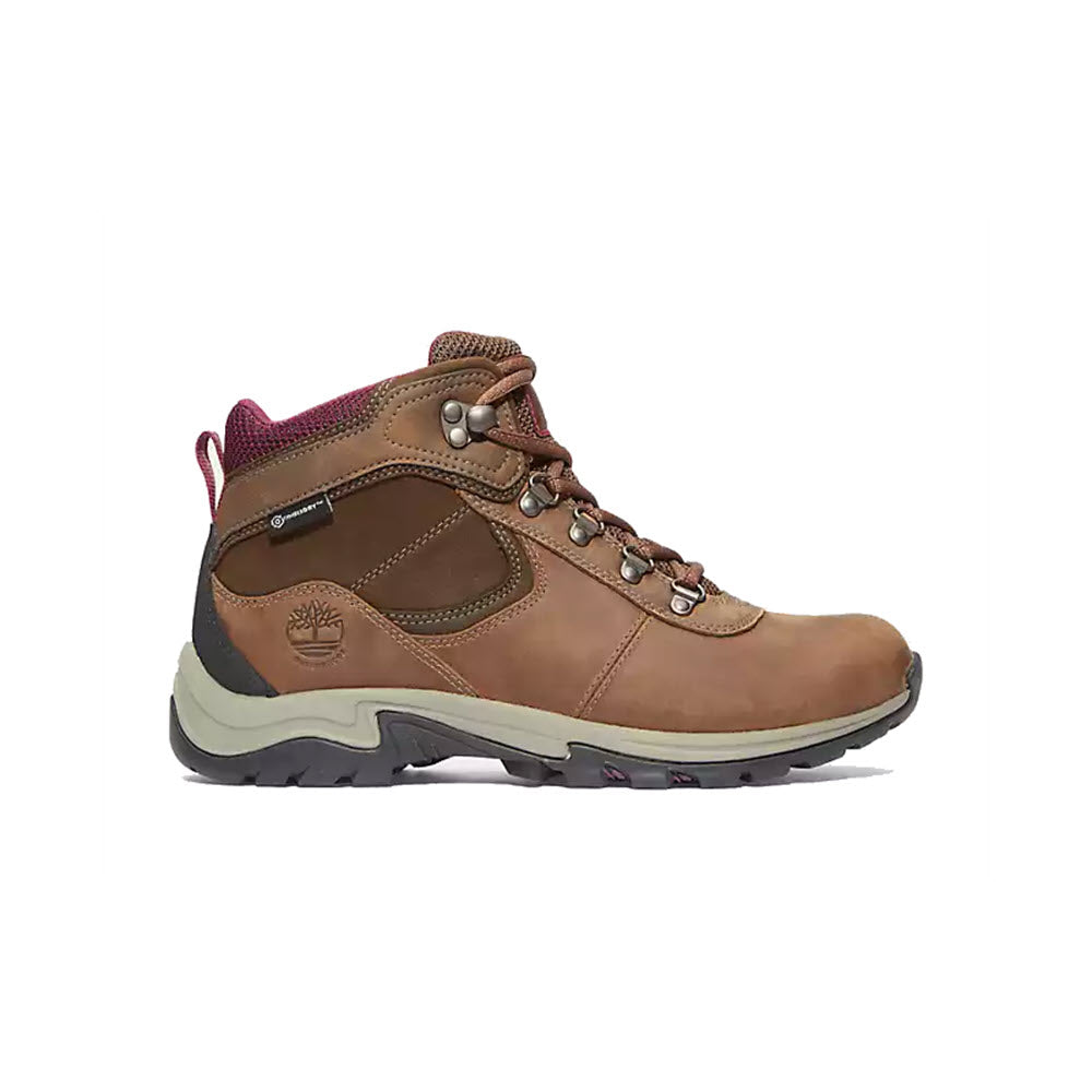 A brown and pink Timberland Mt. Maddsen Mid Waterproof Medium Brown women&#39;s hiking boot with metal eyelets on a white background.