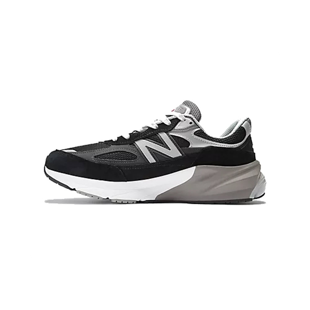 A New Balance 990v6 running shoe, featuring black and gray tones with a prominent &quot;n&quot; logo on the side, displayed against a white background.