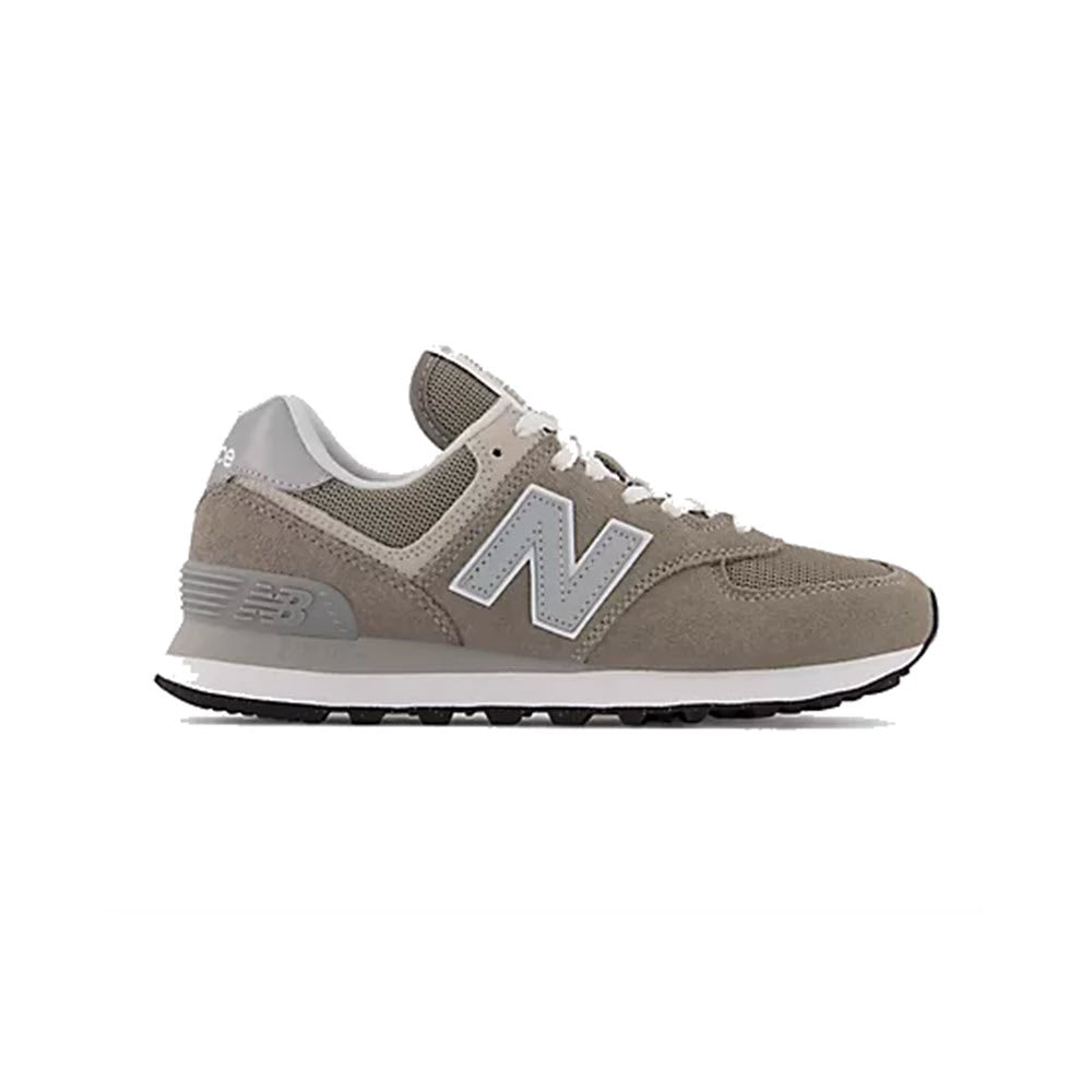Side view of a grey New Balance 574 Grey - Womens sneaker with a large white &quot;N&quot; logo on the side, set against a white background.