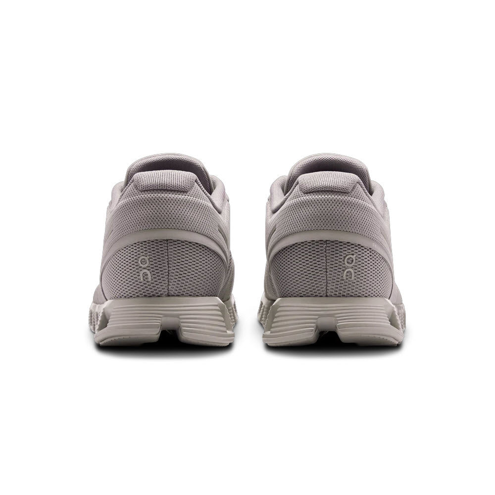 Rear view of a pair of On Running Cloud 5 Fog/Alloy sneakers featuring a speed lacing system, on a white background, showing textured soles and mesh fabric.