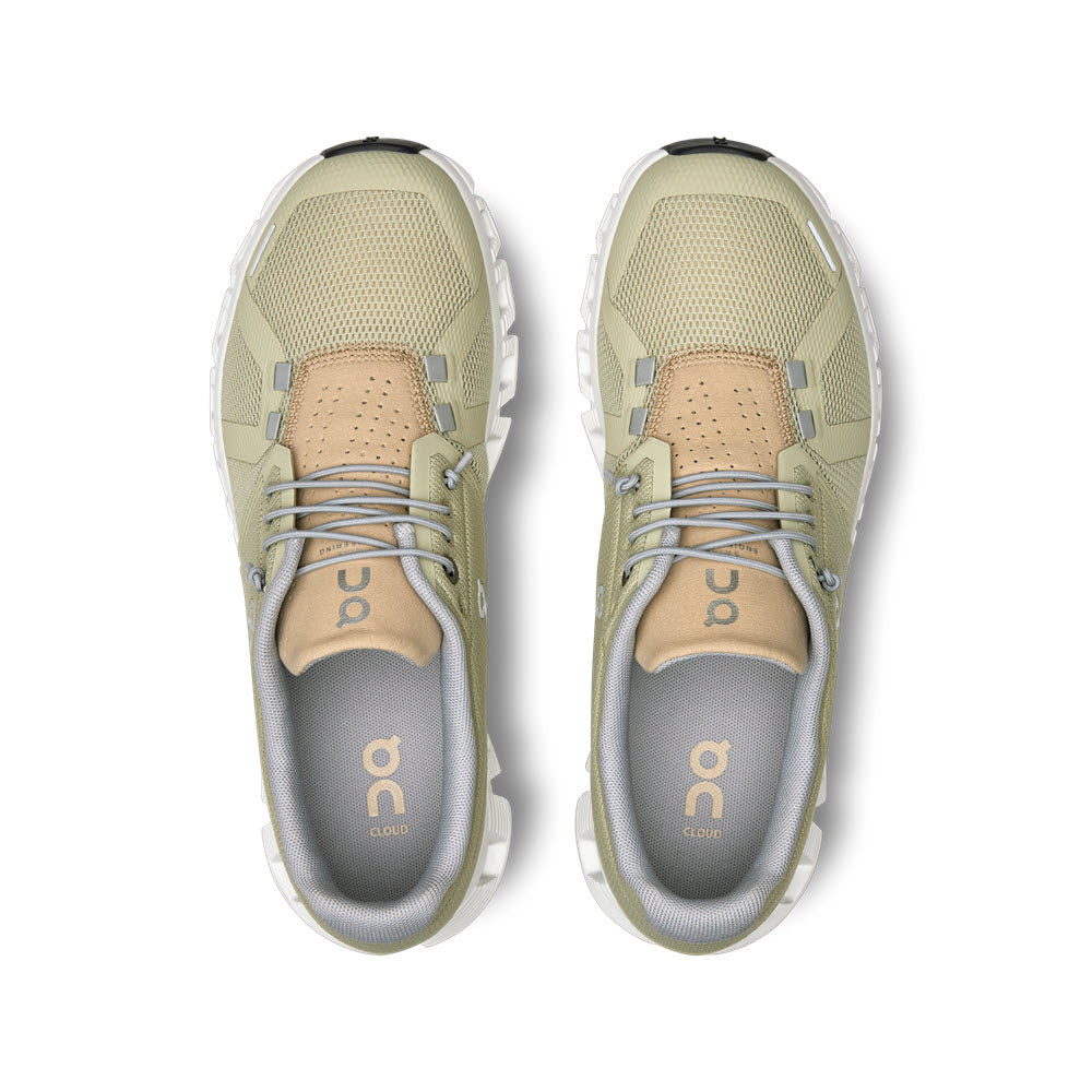 A pair of ON CLOUD 5 HAZE/SAND - WOMENS athletic shoes with beige accents, viewed from above, showcasing the On Running brand logo on the insoles and designed for more comfort.