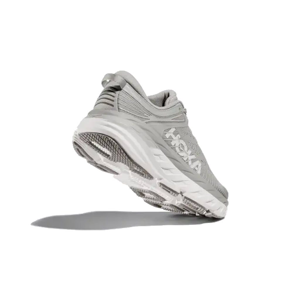Grey Hoka running shoe shown from the side, slightly elevated, displaying the sole and cushioning. This HOKA BONDI 7 HARBOR MIST - WOMENS road shoe features Meta-Rocker technology for a smoother stride.