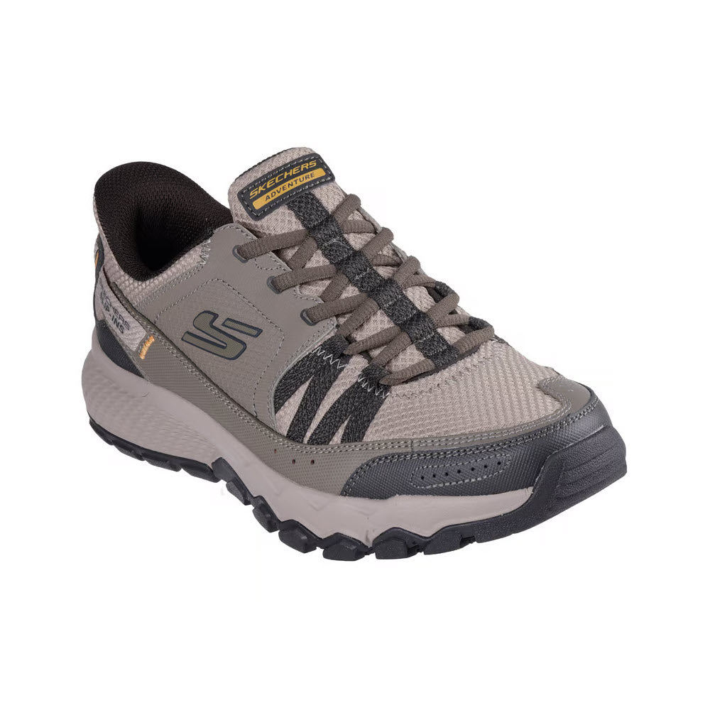 The SKECHERS DYNAMITE AT ESCAPAR SLIP INS TAUPE - MENS features taupe and black hues, textured fabric, black laces, rugged sole, memory foam insole, and Skechers branding—ideal outdoor shoes for men. Displayed on a white background.