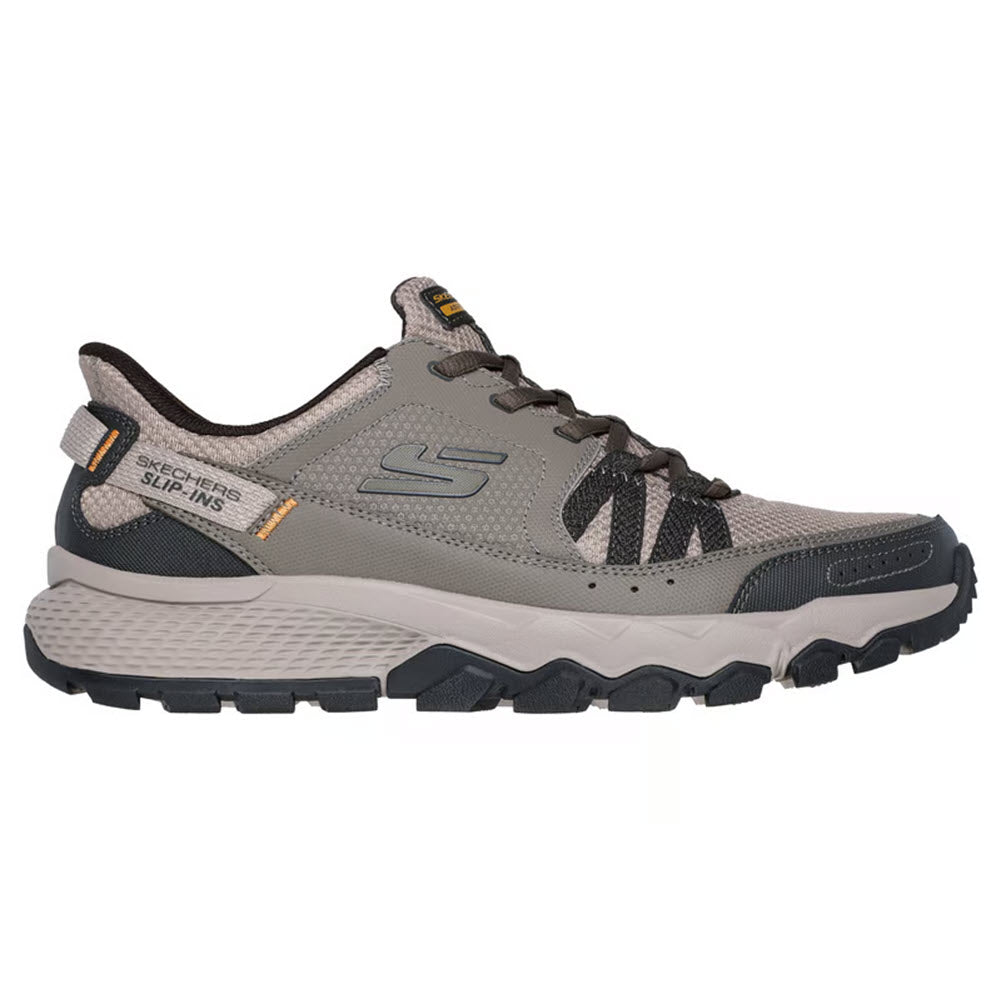 The SKECHERS DYNAMITE AT ESCAPAR SLIP INS TAUPE for men are taupe slip-ins by Skechers, featuring a mesh upper, textured sole, orange details, lace-up front, and cushioned memory foam insole—perfect for outdoor comfort and shown from the side.