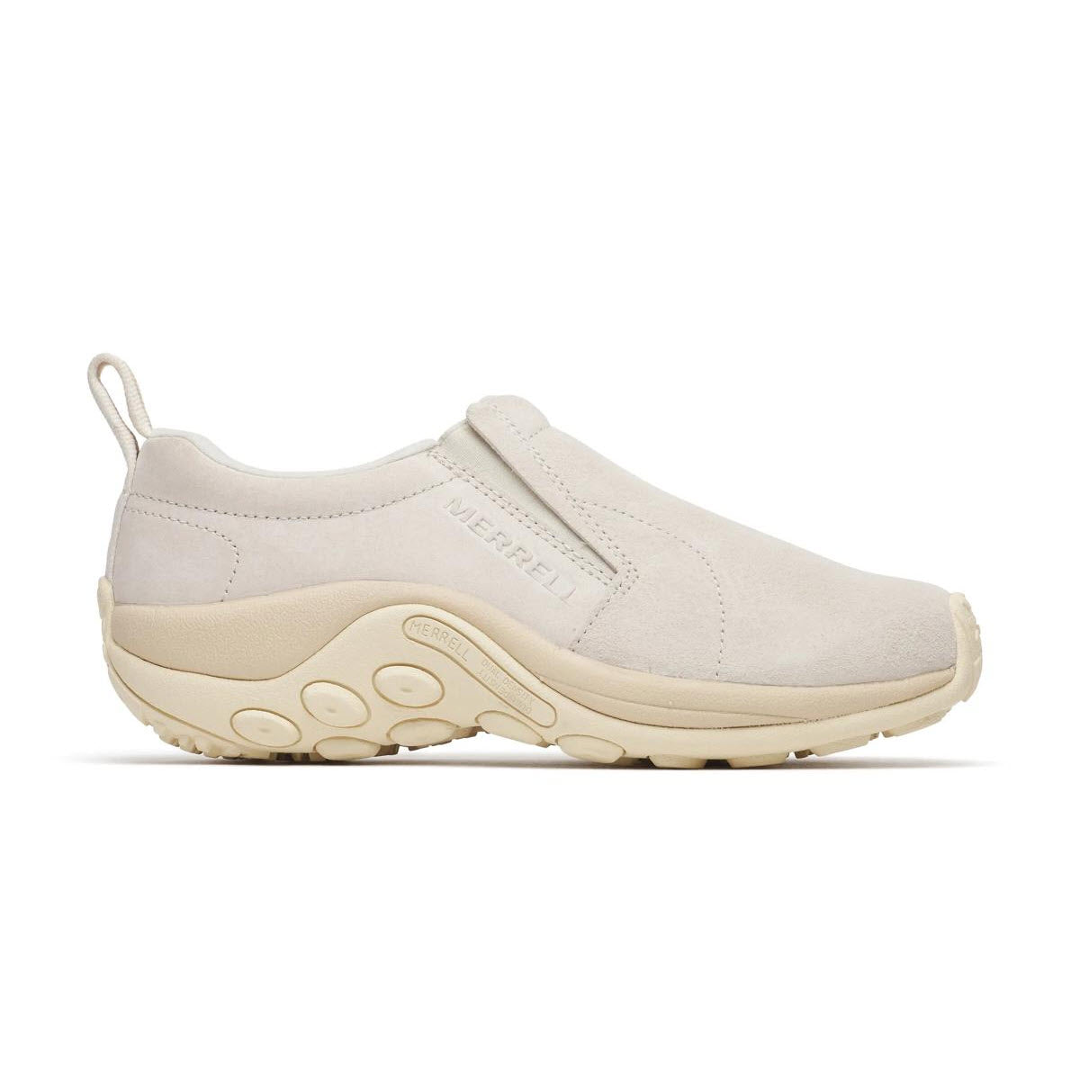 A beige Merrell slip-on shoe with a suede upper, round toe, thick rubber sole, and textured grip. The shoe features a pull tab at the heel and subtle stitching details.