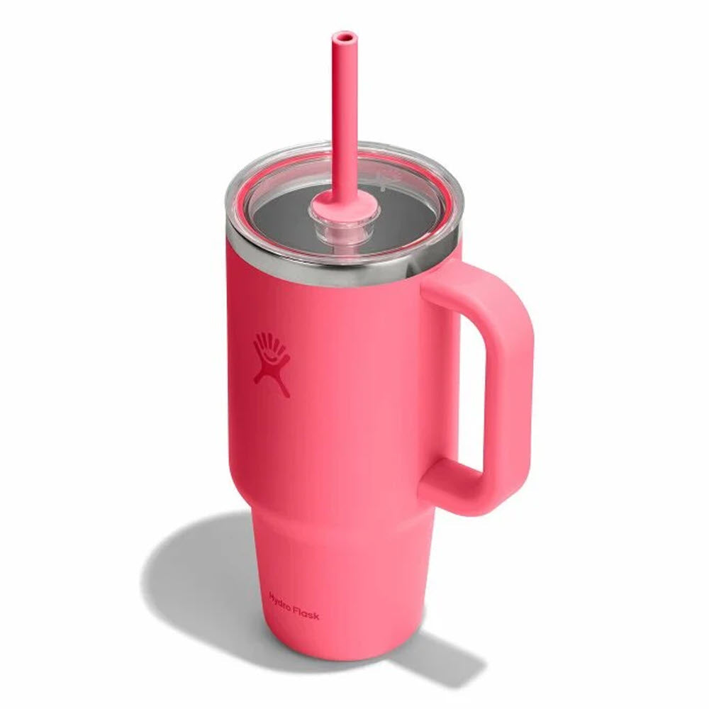 A pink insulated tumbler with a handle, clear lid, and matching pink straw is shown on a white background. The cup features a small logo on the front.