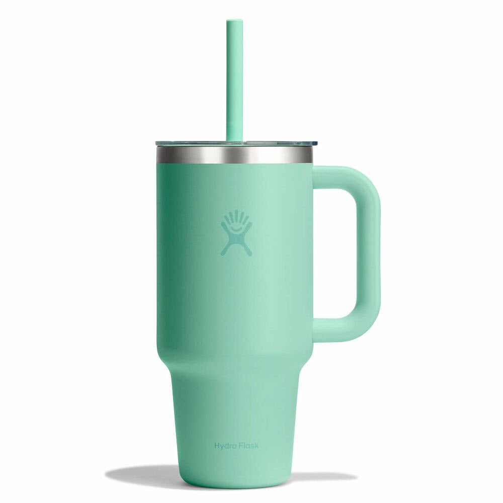 A light teal Hydro Flask tumbler with a handle, stainless steel rim, matching straw, and a subtle logo on the front. The tumbler is standing upright against a white background.
