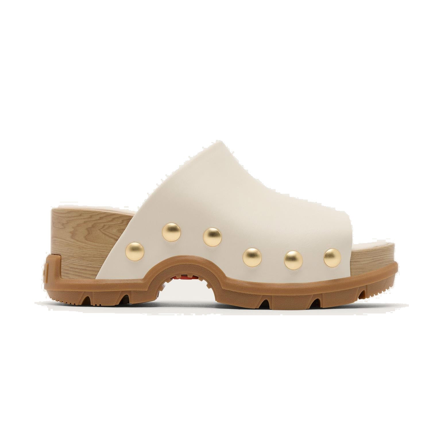 A stylish mule sandal with a chunky tan sole, wooden platform heel, cream upper, and gold stud accents along the side. The shoe has a modern yet rustic look.
