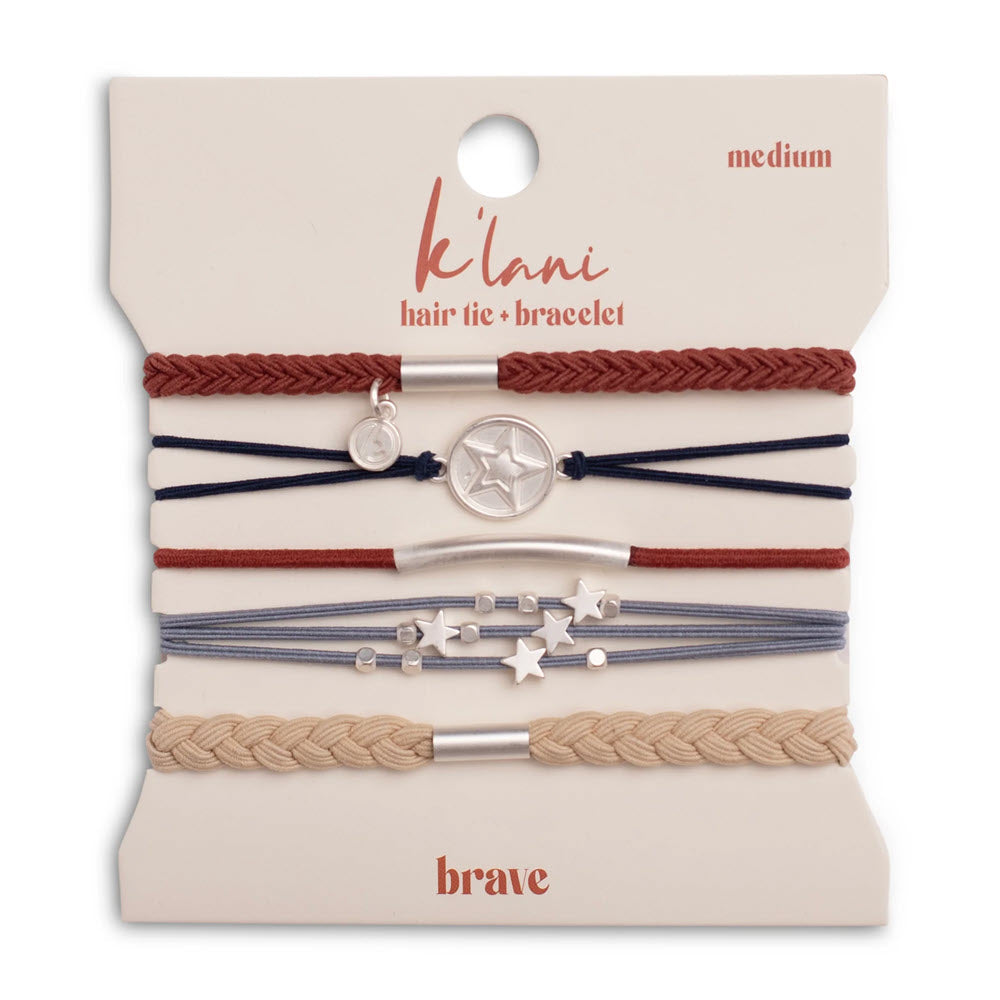 Five assorted braided and corded hair tie bracelets in red, navy, and beige with silver star and charm decorations, displayed on a card labeled klani hair tie + bracelet medium, brave.