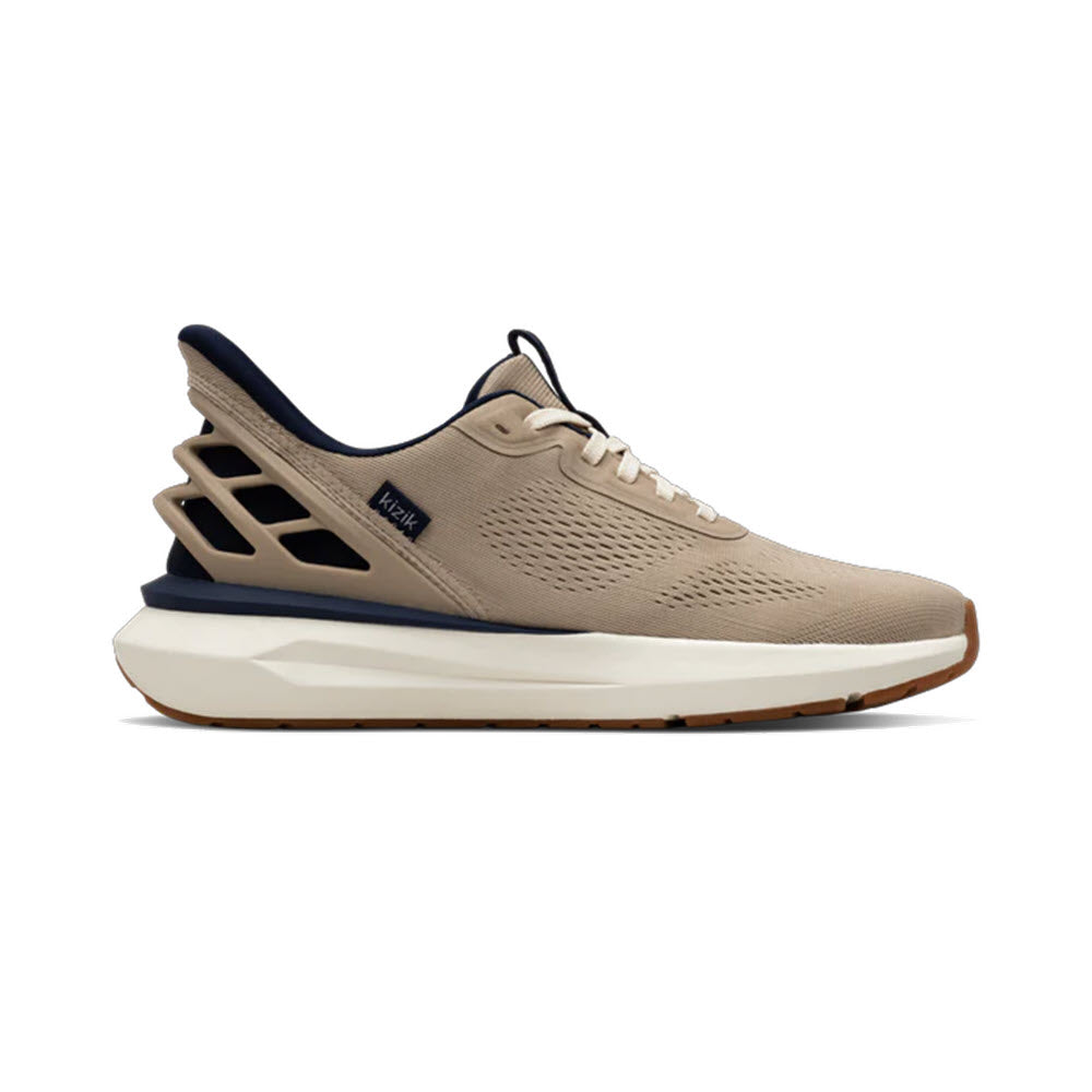 A beige athletic sneaker with a white sole, navy blue inner lining, and an open, geometric heel design. The shoe features a breathable mesh upper and a small label on the side.