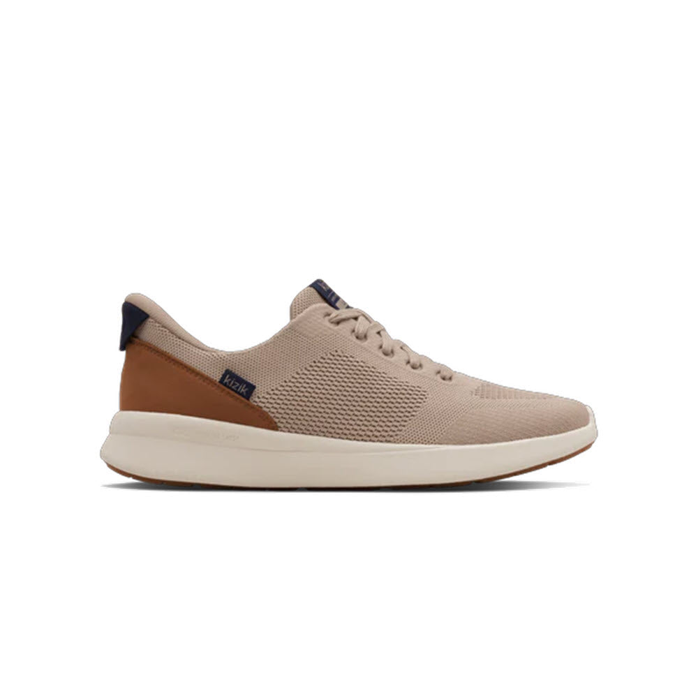A beige lace-up sneaker with a mesh texture, brown leather heel accent, white sole, and subtle navy blue tag near the heel, displayed on a white background.