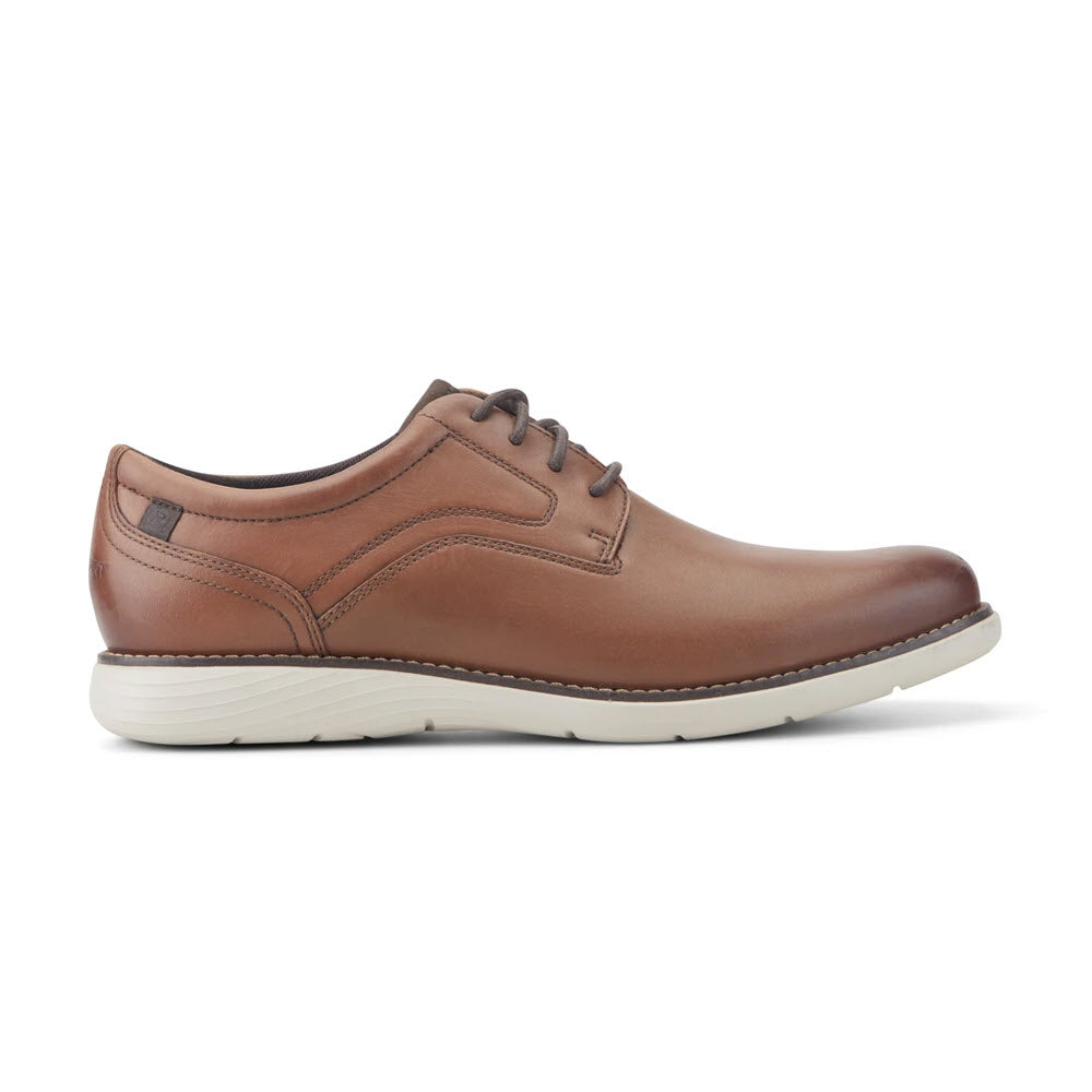A brown leather lace-up dress shoe with a white rubber sole, featuring visible stitching and a low heel, shown from the side on a plain white background.