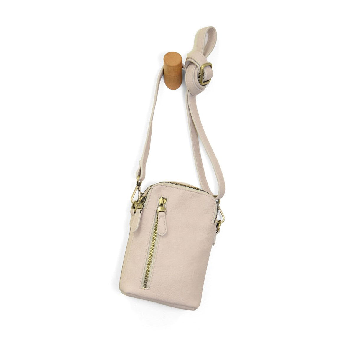 A small beige crossbody bag with a gold zipper pocket on the front, hanging by its strap from a wooden peg on a white background.
