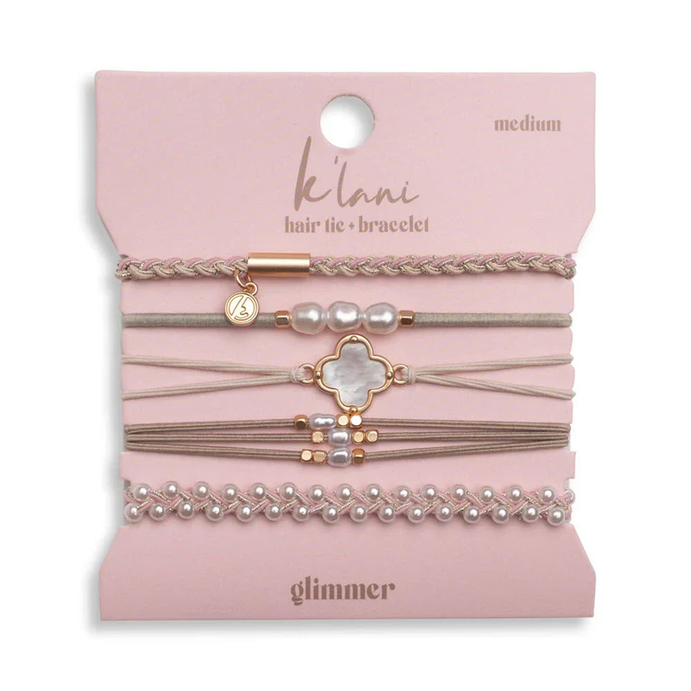A set of six pink and beige hair ties and bracelets with gold, pearl, and flower accents is displayed on a pink card labeled klani hair tie + bracelet, medium, glimmer.