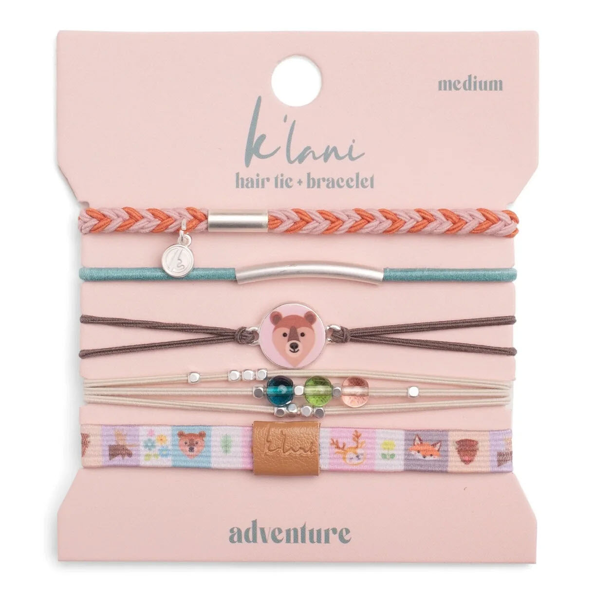 A set of five colorful hair ties and bracelets on a card labeled klani. Designs include a braided band, a teal band, a bear charm, beads, and a band with animal illustrations. The card reads medium and adventure.