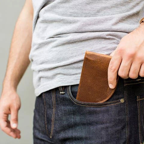 A person sliding a Rogue Front Pocket Wallet Leather Brown into their front pocket.