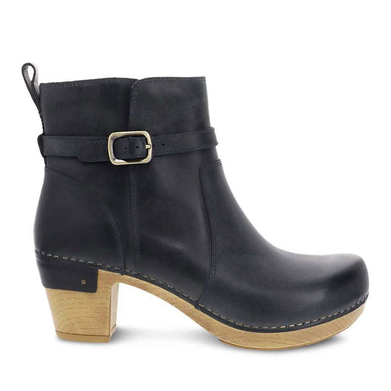 Dansko Anya Denim Waxy Burnished women&#39;s black ankle boot with buckle detail, stain resistance, and a wooden heel.
