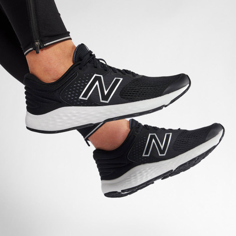 A person wearing black and white New Balance 520V7 women&#39;s running shoes with a prominent &quot;n&quot; logo on the sides.