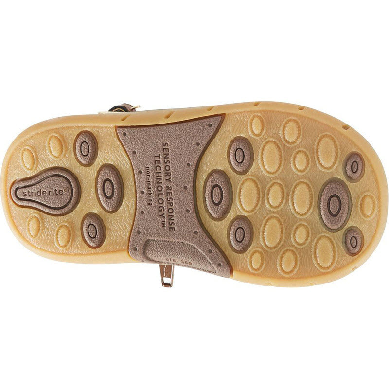 Sole of a child&#39;s Stride Rite SRT Agnes Brown boot with rubber traction circles and a label identifying the brand as &quot;Stride Rite&quot; with Sensory Response Technology.