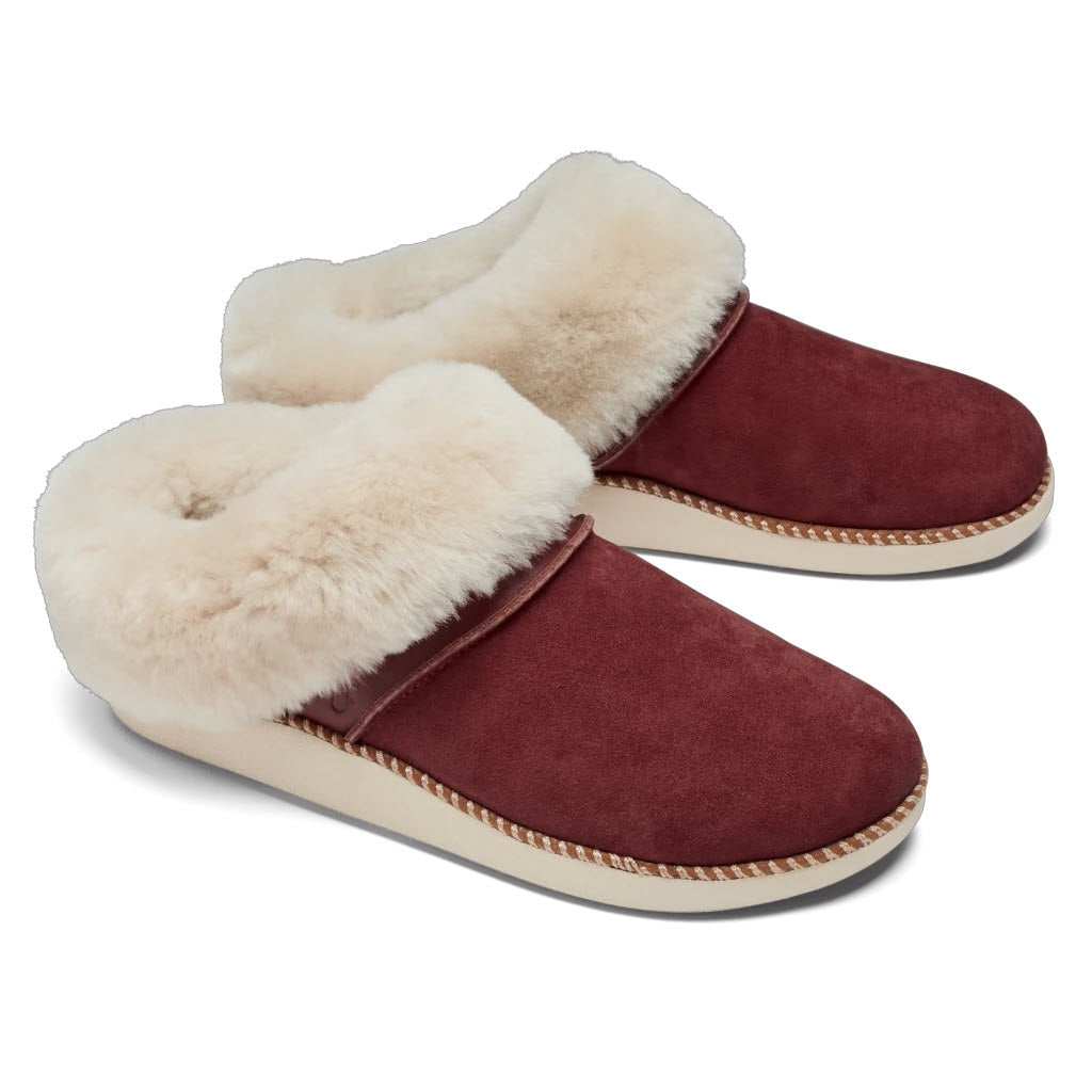 A pair of maroon Olukai kui canoe/tan sheepskin slippers with fluffy shearling-lined lining on a white background.