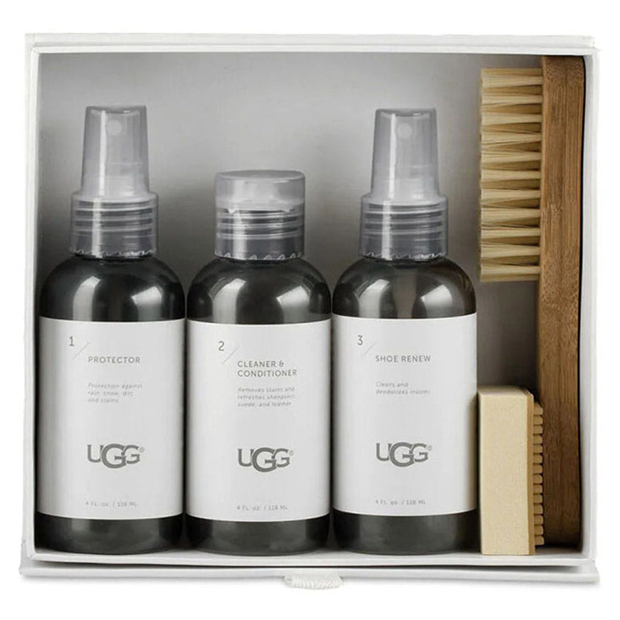 A UGG Care Kit with sheepskin protector, cleaner &amp; conditioner, and renewer sprays displayed next to a brush.